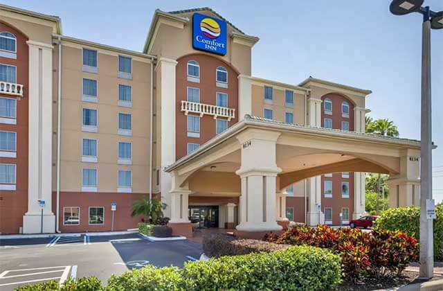 front exterior of brown building with entrance and drop-off area at comfort inn international drive orlando