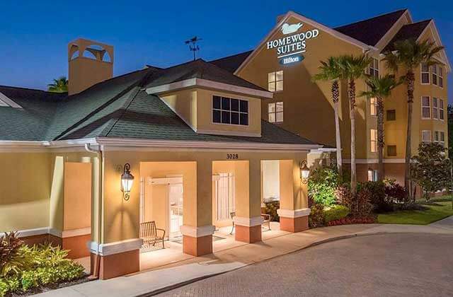 front exterior of hotel at night with duck logo at homewood suites by hilton orlando ucf area