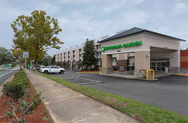 front exterior of hotel with parking drop-off and trees at wyndham garden tallahassee capitol