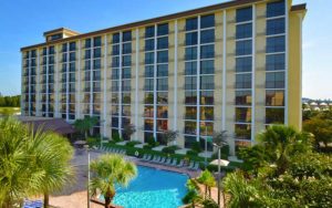 front exterior hotel with pool and palm trees at rosen inn