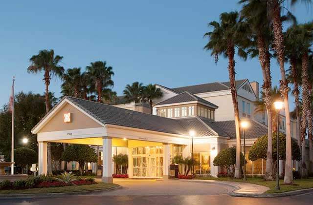 front exterior of hotel at night with drop-off and palm trees at hilton garden inn orlando airport