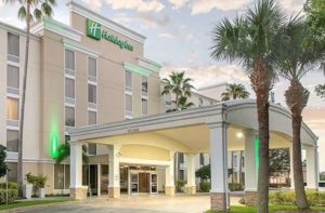 front exterior with sunrise entrance drop off area and palm trees at holiday inn melbourne viera conference center