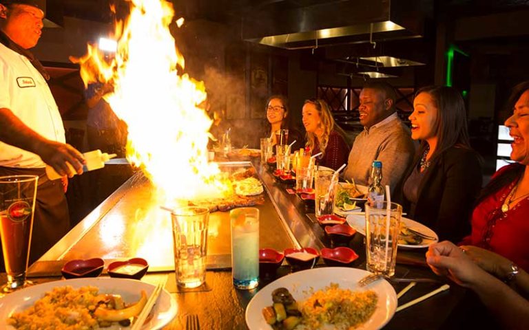 group of diners watching hibachi chef cooking with flame at rosen inn