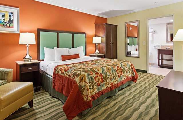 hotel room with colorful floral pattern king size bed at best western plus palm beach gardens hotel and suites conference center