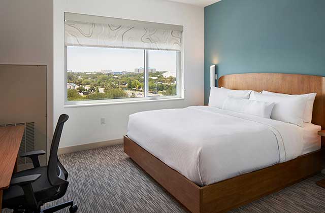 hotel room with king size bed large window with view and desk at element orlando international drive