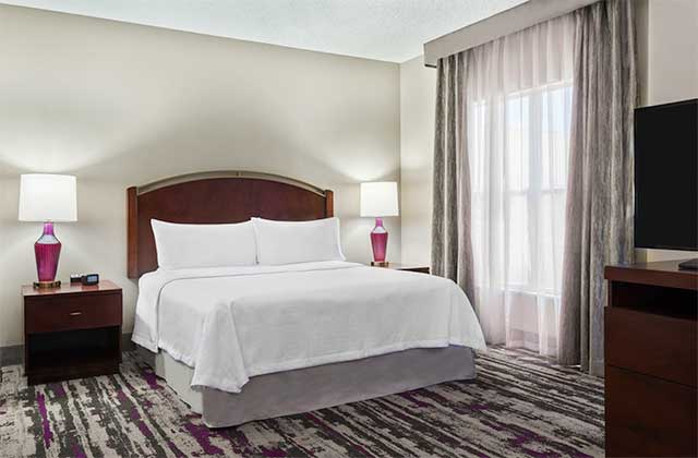 hotel room with king size bed and gray accents at homewood suites by hilton orlando ucf area