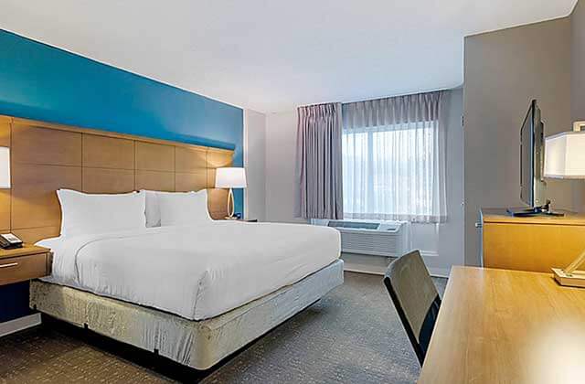 hotel room with king size bed desk tv window and blue accent wall at staybridge suites orlando royale parc suites
