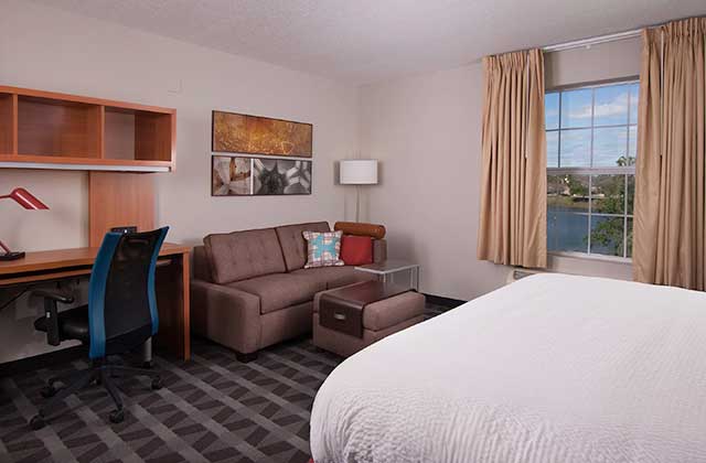 hotel room with large bed sofa and desk at towneplace suites the villages