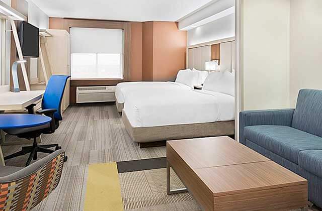 hotel room with large beds desk sofa and blue accents at holiday inn express and suites nearest universal orlando