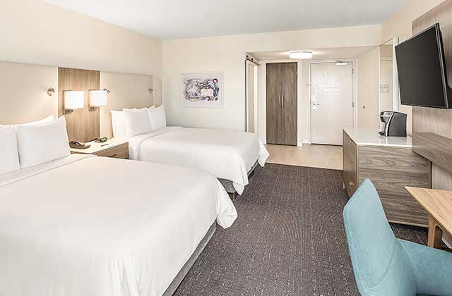 hotel room with two beds and blue chair at desk at crowne plaza orlando lake buena vista