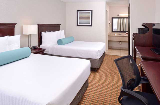 hotel room with two king size beds with blue bolsters a desk and bathroom at best western international drive orlando