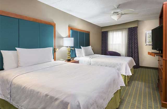 hotel room with two large beds with blue and green accents at homewood suites by hilton orlando nearest to universal studios