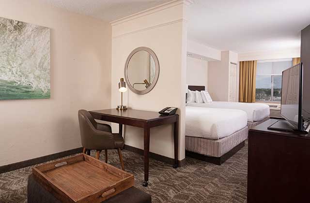 hotel room with two large beds desk and gold curtains at springhill suites orlando airport