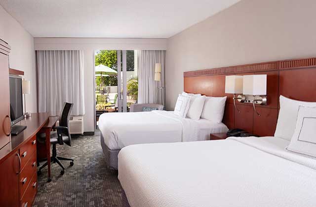 hotel room with two large beds and patio doors to pool area at courtyard miami coral gables