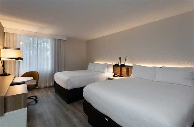 hotel room with two queen beds desk and windows in white and dark wood design at wyndham garden tallahassee capitol