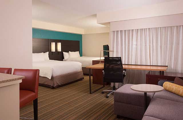 large hotel room with two beds desk sofa and red and teal accents at residence inn by marriott orlando convention center