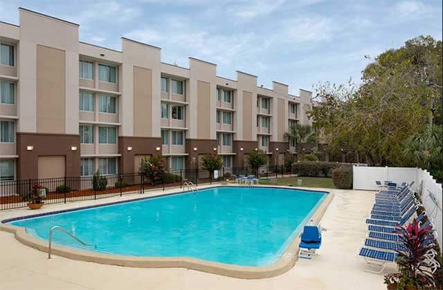 large pool with blue lounge chairs and trees at wyndham garden tallahassee capitol