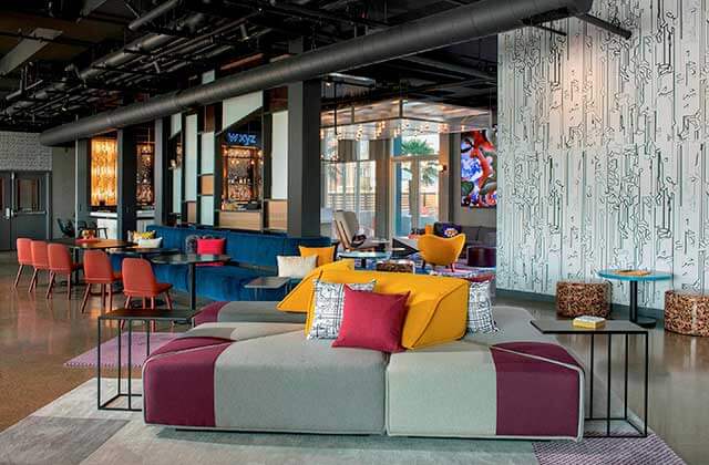 lobby area with yellow cushions pink chairs and blue sofas at aloft orlando international drive