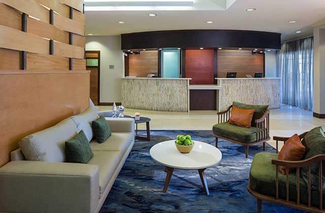 lobby front desk and lounge with green chairs and blue rug at fairfield inn and suites orlando lake buena vista