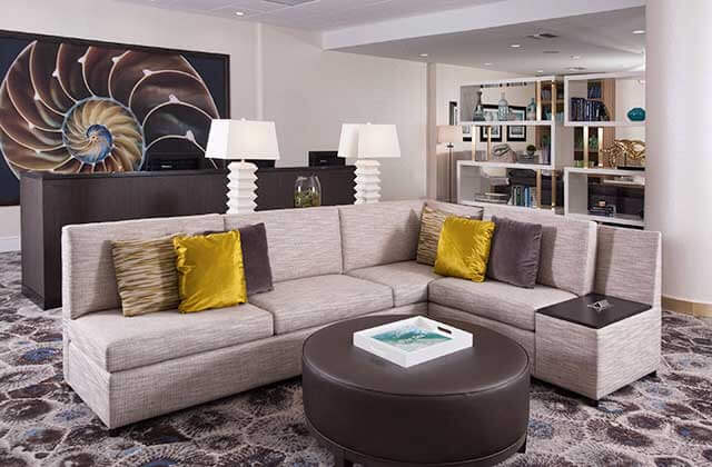lounge area with gray sofas and shell design art on wall at courtyard miami coral gables