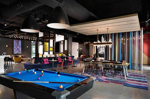 lounge area with vaulted black ceilings pool table and colorful accents at aloft orlando international drive