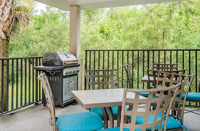 outdoor covered patio with bbq grill metal tables and chairs with blue cushions at candlewood suites fort myers sanibel gateway