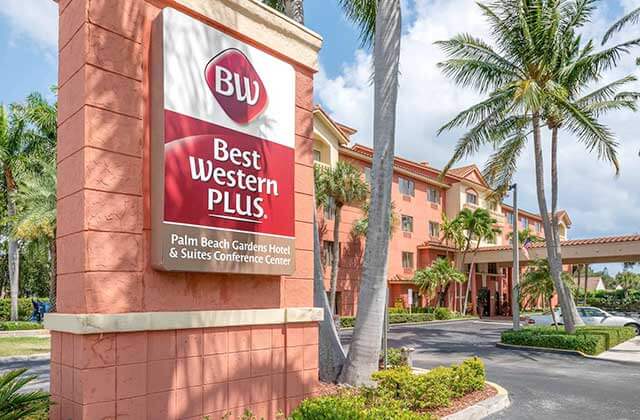 outdoor exterior of hotel with coral colored sign at best western plus palm beach gardens hotel and suites conference center