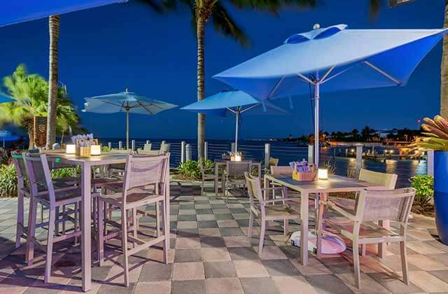 outdoor patio at night overlooking water with blue umbrellas at courtyard marathon florida keys