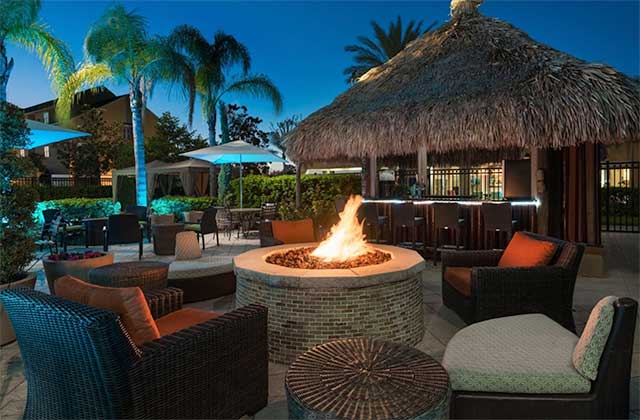 outdoor patio at night with firepit and tiki bar at hilton garden inn orlando international drive north