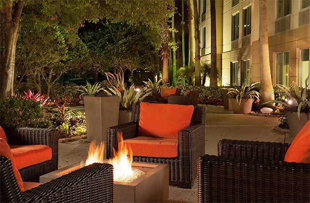 outdoor patio at night with orange seating and fire pit at hilton garden inn orlando airport