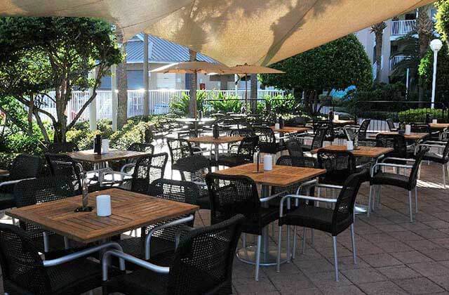 outdoor patio seating with beige awnings and umbrellas at clarion suites maingate