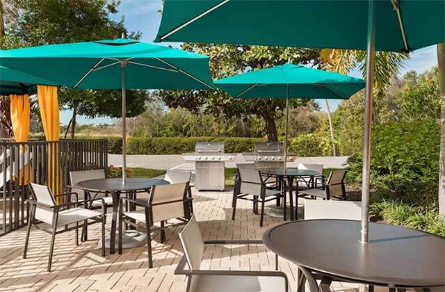 patio area near pool with grills tables and teal umbrellas at hampton inn ellenton bradenton florida