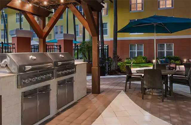 patio area with two grills and blue umbrella at homewood suites by hilton orlando ucf area