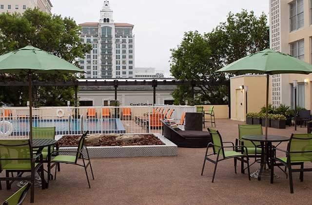 pool and patio area with green umbrellas and orange chairs at courtyard miami coral gables