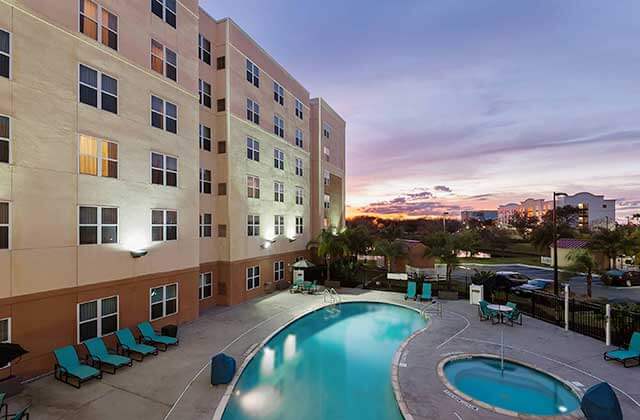 pool area at night with jacuzzi and blue chairs at residence inn by marriott orlando airport