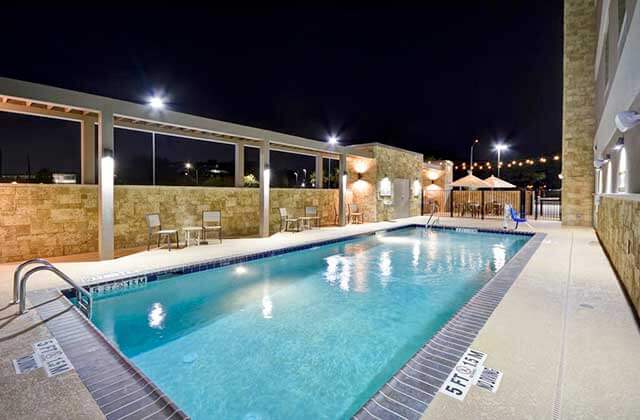 pool area at night with stone facades and chairs at home2 suites by hilton palm bay i-95