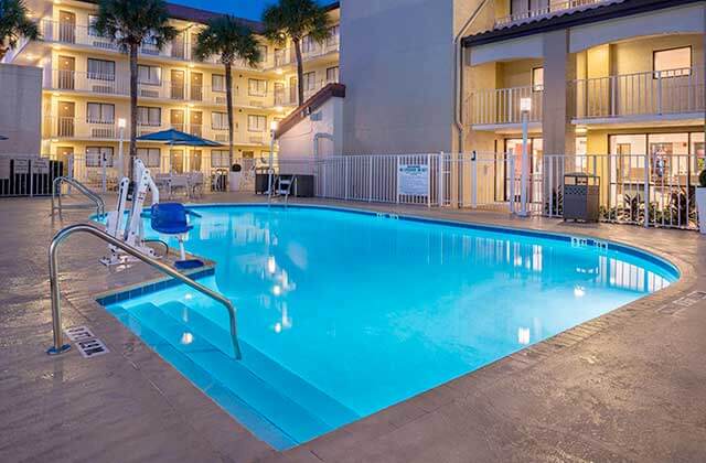 pool area with blue lighted water at night with accessible rig and balconies at best western international drive orlando