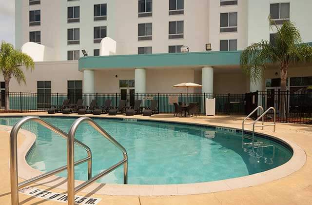 pool area with black seating and brown umbrella at springhill suites orlando airport