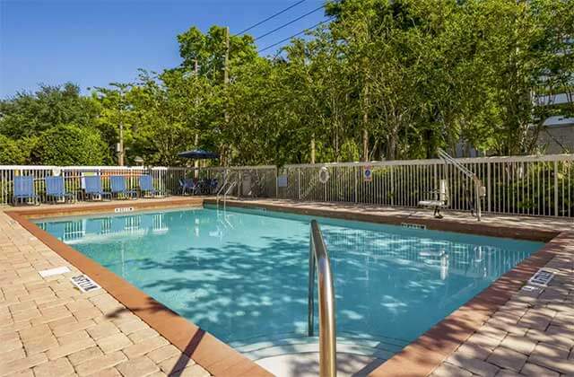 pool area with blue chairs white fence and trees at comfort inn international drive orlando