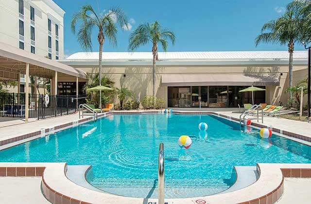 pool area with colorful chairs umbrellas and palm trees at holiday inn melbourne viera conference center