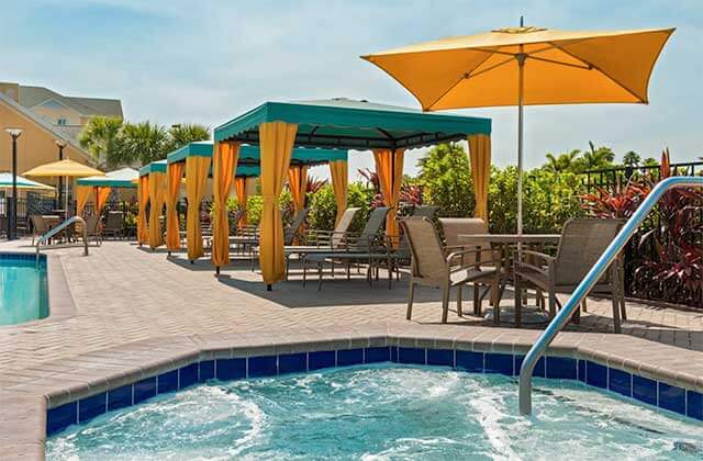 pool area with jacuzzi and green and orange cabanas and umbrellas at homewood suites by hilton orlando nearest to universal studios