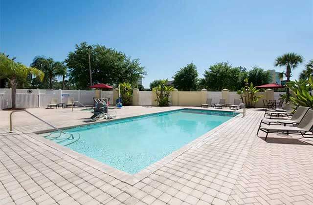 pool area with lounge chairs and red umbrellas at comfort suites near universal orlando resort