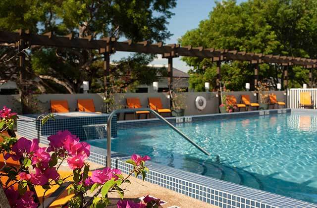 pool area with pergola and orange chairs at courtyard miami coral gables