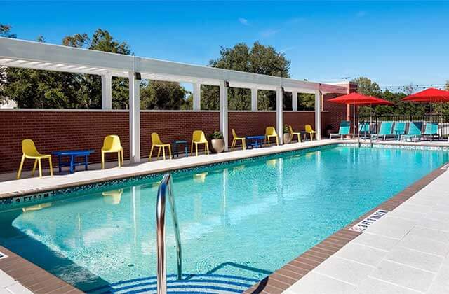 pool area with yellow chairs blue lounges and red umbrellas at home2 suites by hilton orlando near ucf