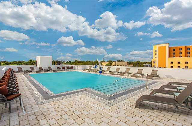 rooftop pool deck with orange seating and blue cloudy sky at wyndham garden ft lauderdale airport and cruise port
