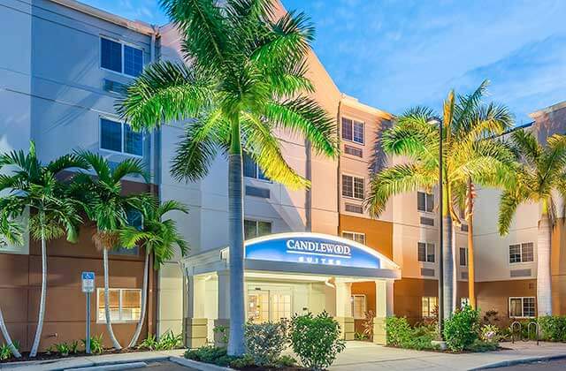 up-lighted front exterior hotel building with palm trees at twilight candlewood suites fort myers sanibel gateway