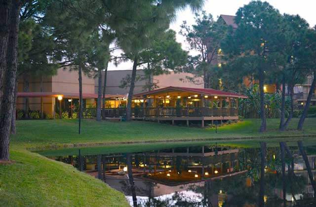view across water of pavilion dining at night with trees at rosen inn lake buena vista