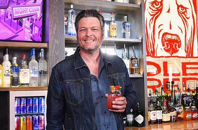 celebrity owner standing behind a bar with a drink in hand at blake sheltons ole red orlando icon park