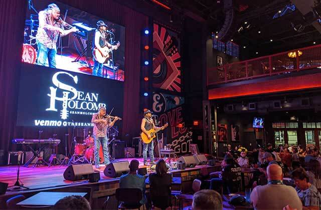 country music performers on stage with crowded dining areas and red lighting at blake sheltons ole red orlando icon park