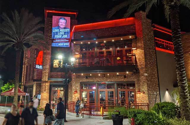 exterior at night of two-story restaurant with brick and red lighting at blake sheltons ole red orlando icon park